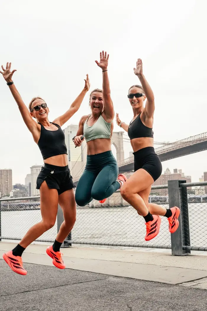 Three women jumping for joy by the East River
