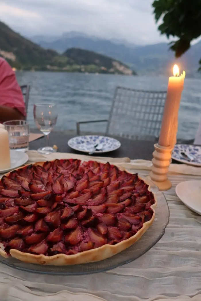 A strawberry tart on a candlelit table beside a lake
