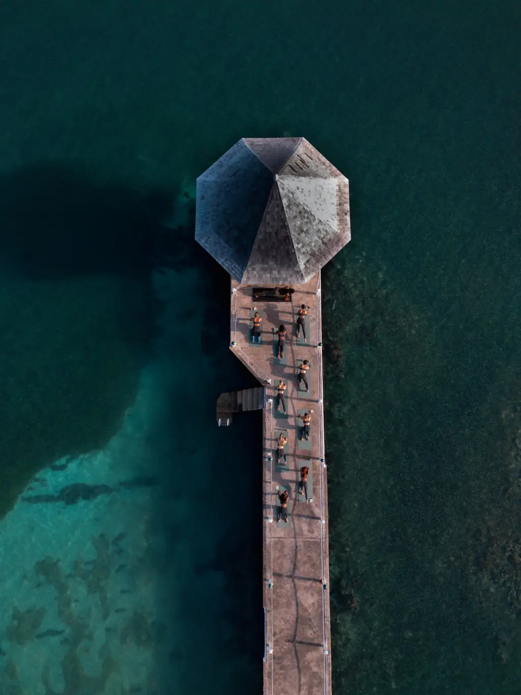 An aerial view of a yoga class on a pier over turquoise water in Jamaica