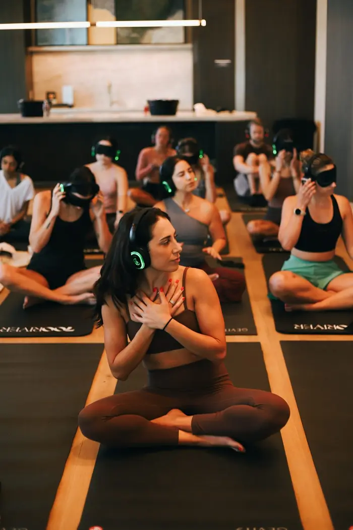 A guided breathwork session, with guests on mats wearing headphones